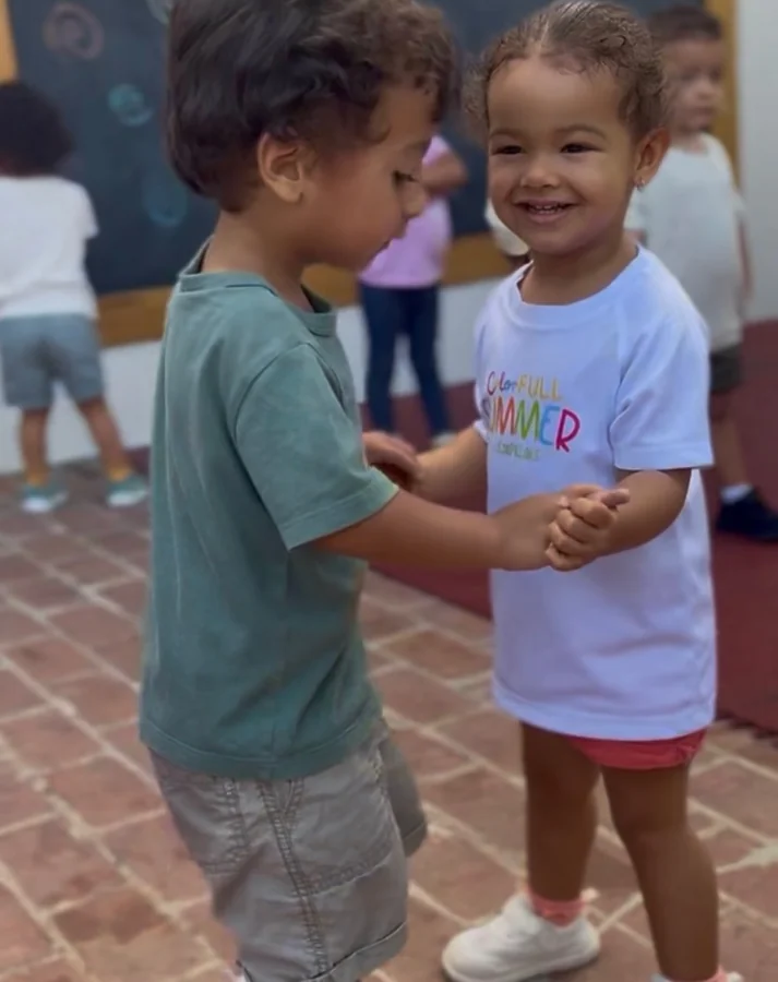 Dos niños pequeños se dan la mano al llegar a la escuela