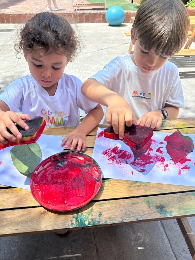 Dos niños estampan pintura juntos sobre el mismo papel