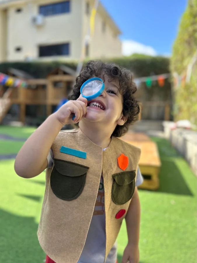 Un niño observa con una lupa en el jardín de Colorpillars