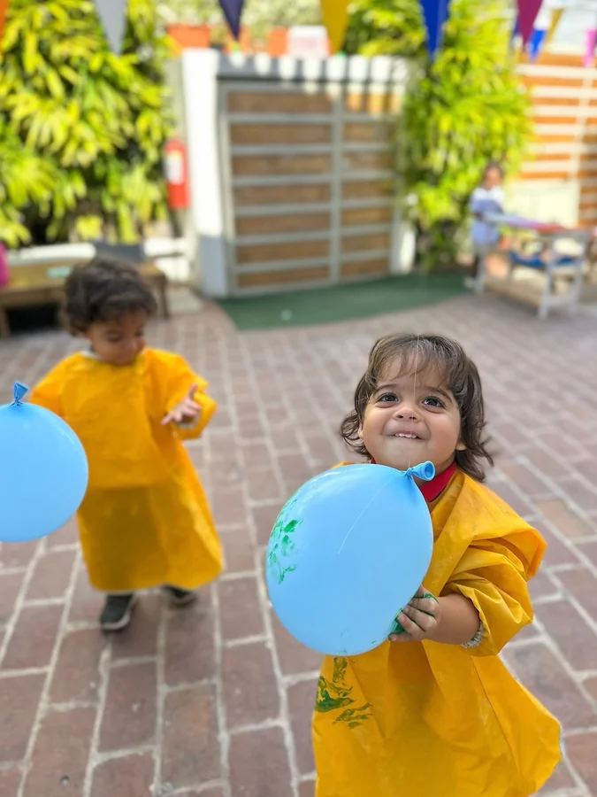 Una niña corre con un globo azul en el patio