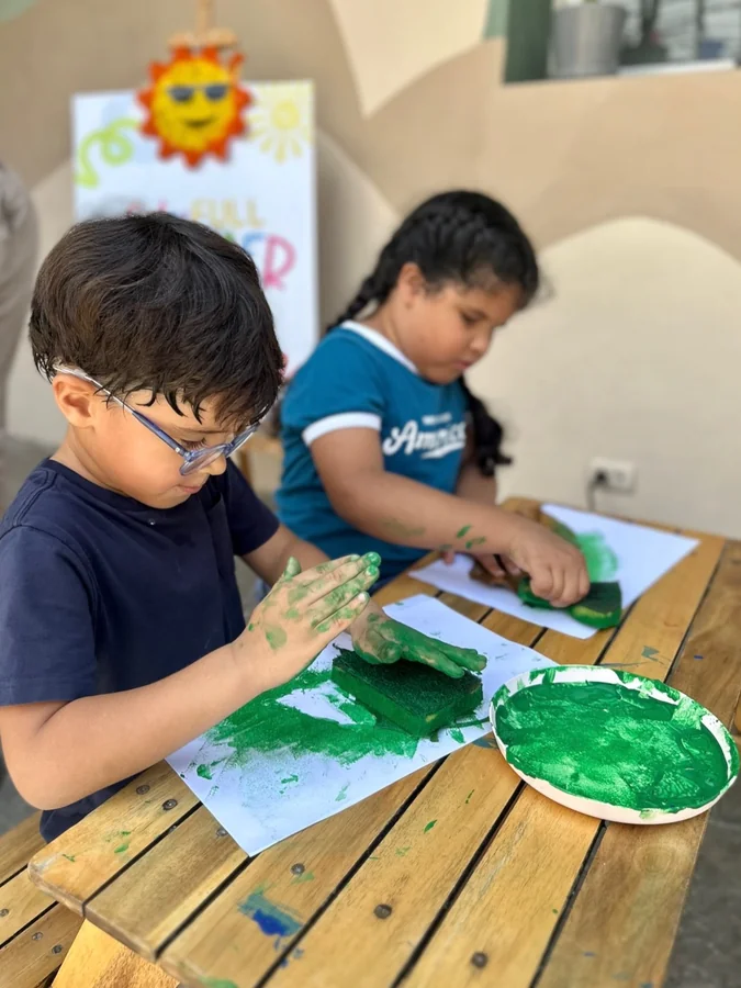 Dos niños pintan concentrados en la mesa del aula