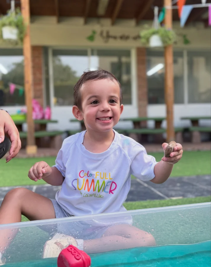 Un niño juega en la mesa de agua del jardín
